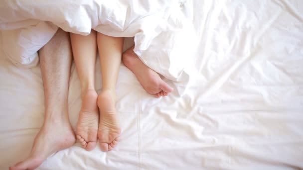 Un uomo e una donna a letto. vista superiore gambe maschili e femminili, biancheria bianca — Video Stock