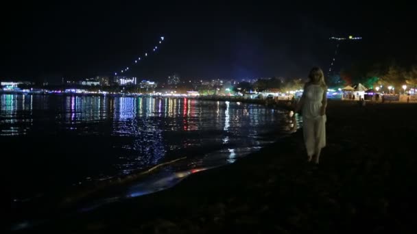 Dívka v dlouhých bílých šatech. procházky po pláži v noci. — Stock video