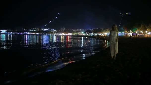 Chica en un vestido blanco largo. paseos por la playa por la noche . — Vídeos de Stock