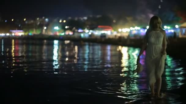 Mädchen in einem langen weißen Kleid. Spaziergänge am Strand in der Nacht. — Stockvideo