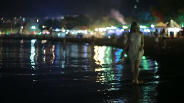 Κορίτσι σε ένα μακρύ λευκό φόρεμα. περιπάτους κατά μήκος της παραλίας το βράδυ. — Αρχείο Βίντεο