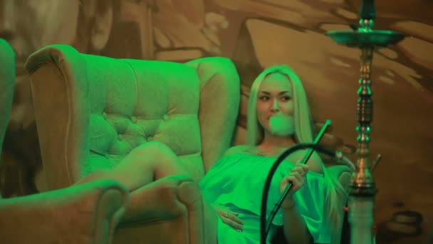 Mujer Beautifu inhalando narguile. chica fumar shisha acostado en sofá en la cafetería . — Vídeos de Stock
