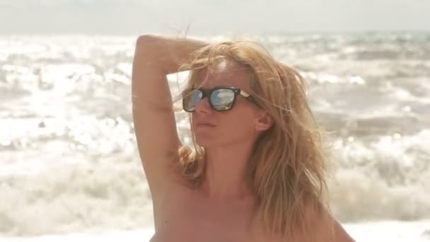 Vacker ung kvinna i solglasögon. mot bakgrund av havet. — Stockvideo