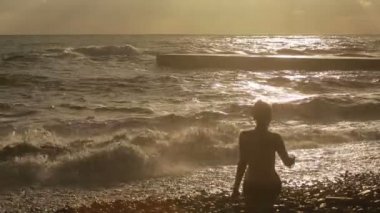 Deniz kenarında oturan kız. büyük dalgalar. siluet figürler