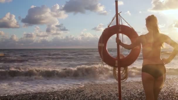 Baksidan av en vacker flicka. Flickan står i havet nära livslinjen. — Stockvideo