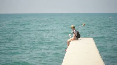 Deniz kenarında ayakta seyahat adam gülümsüyor. turist denizde bir sırt çantası ile.