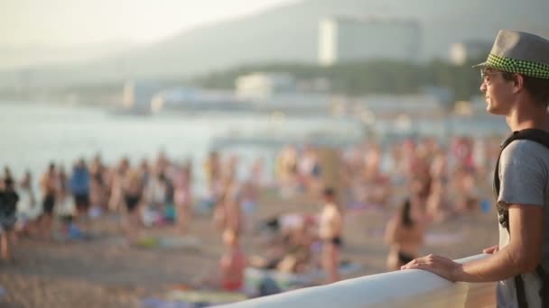 Ταξίδια χαμογελαστός άνθρωπος που στέκεται δίπλα στην παραλία. τουρίστας με ένα σακίδιο στην θάλασσα. — Αρχείο Βίντεο