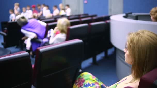 Mujer sentada en una presentación en el teatro. vacaciones escolares . — Vídeo de stock