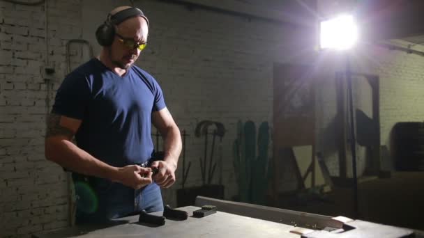 Чоловік готується стріляти з пістолета. поміщає пістолет у кобуру — стокове відео