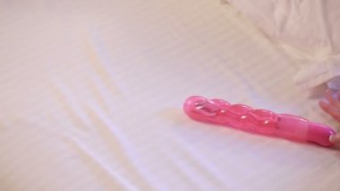 Womans hand reaching for dildo in bed. girl with a sex toy