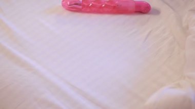Womans hand reaching for dildo in bed. girl with a sex toy