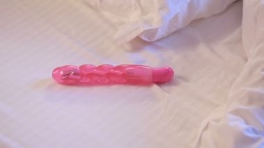 Womans hand reaching for dildo in bed. girl with a sex toy