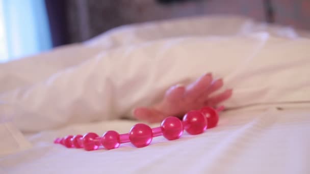 Женская рука тянется к фаллоимитатору в постели. девушка с секс-игрушкой — стоковое видео