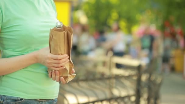 Ragazza che beve da un sacchetto di carta per strada. comportamento antisociale — Video Stock