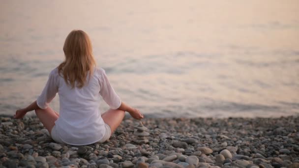 Joven practicando yoga en la playa al atardecer. mar tranquilo — Vídeos de Stock