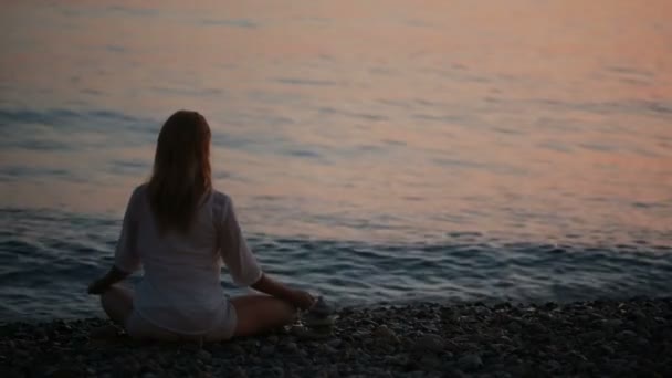 Jovem praticando ioga na praia ao pôr do sol. mar calmo — Vídeo de Stock