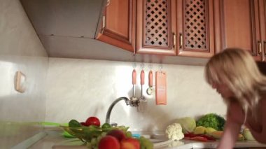 Kız üzüm yıkar. Sebzeler mutfak masasında.