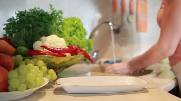 Girl washes corn. vegetables on the kitchen table — Stock Video