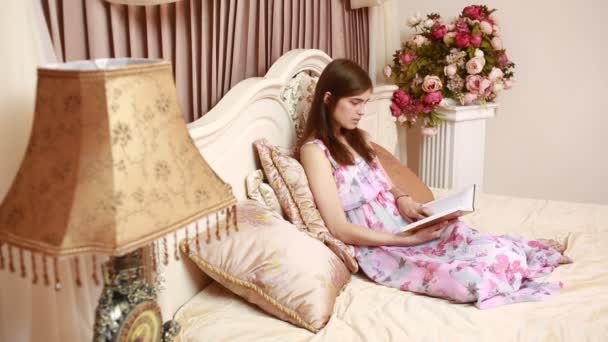 Joven hermosa mujer atractiva, chica, leyendo un libro, acostado en una cama de lujo — Vídeos de Stock