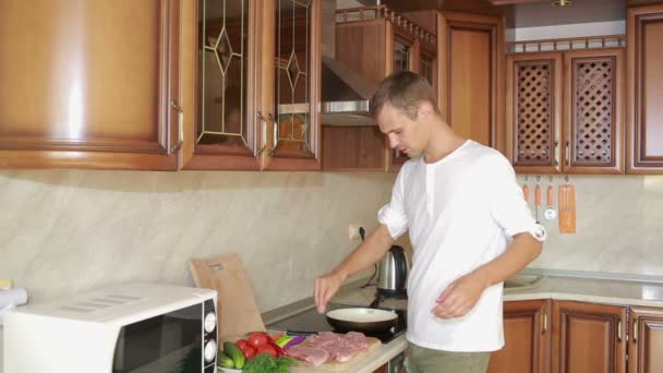 Junger Mann kocht in der Küche. Mann bereitet Fleisch zu — Stockvideo