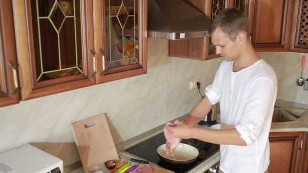 Ung man matlagning i köket. man förbereder kött — Stockvideo