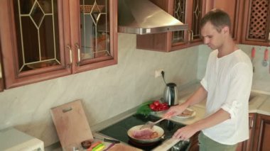 Genç adam mutfakta yemek. adam et hazırlanıyor. Bir tavada kızartma