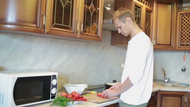 Smiling man preparing salad in the kitchen — Stock Video