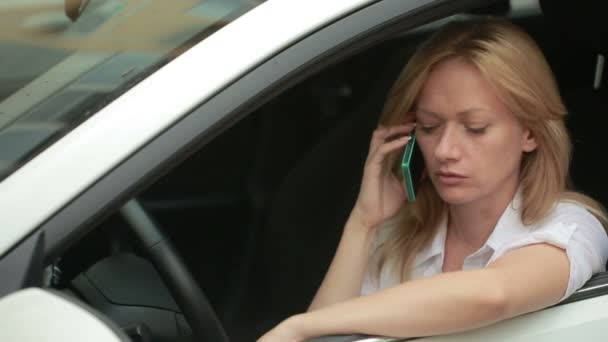 Dziewczyna kierowca rozmawia przez telefon siedząc w samochodzie. Kobieta w parking l — Wideo stockowe