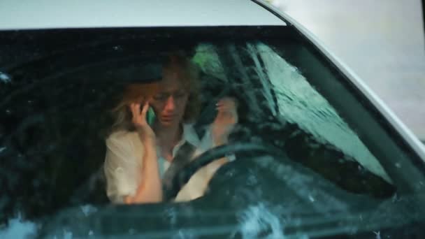 Говорит грустная женщина. девушка плачет в машине. дождь на улице — стоковое видео