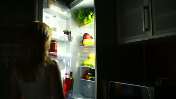 Woman night takes an apple from the fridge. hungry woman — Stock Video