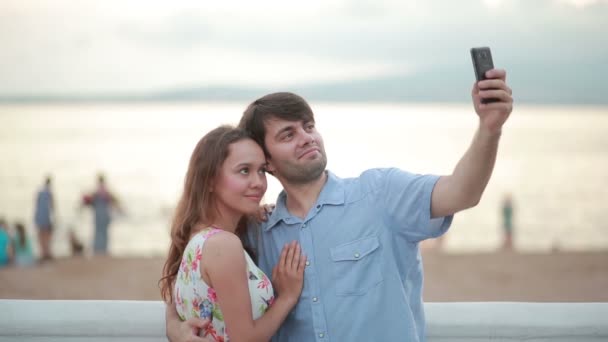 Hermosa pareja tomando selfie dando beso en la playa en verano — Vídeos de Stock