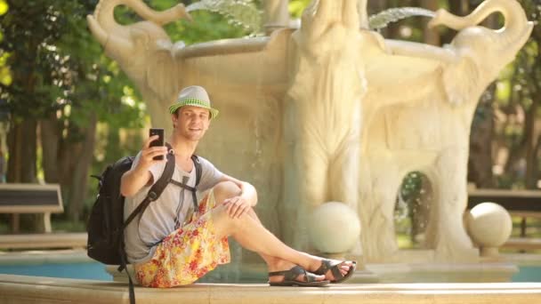 Beau touriste parlant au téléphone à la fontaine. voyage à travers l'Asie — Video