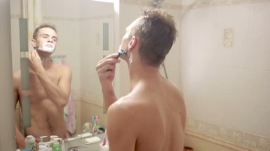 Adam yüzünü tıraş. yakışıklı adam banyoda tıraş.