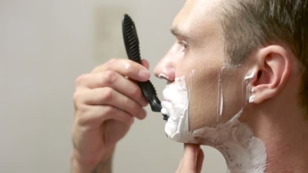 Man shaves his face. handsome man shaving in the bathroom. — Stock Video