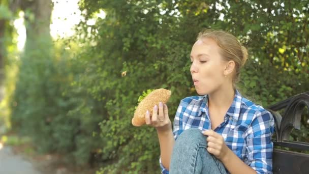 Νεαρή κοπέλα που τρώει ένα σάντουιτς. γρήγορη έννοια των τροφίμων. σάντουιτς δαγκώματα — Αρχείο Βίντεο