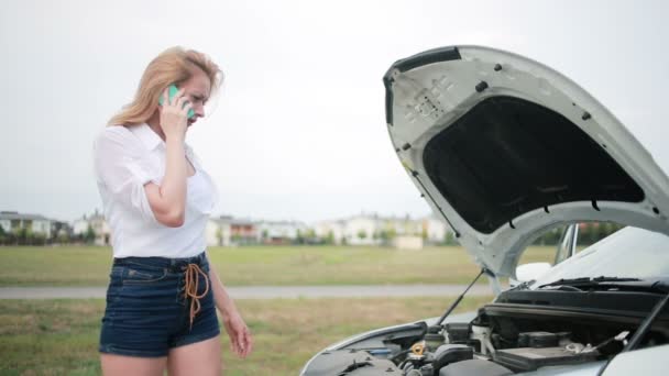 Žena a rozbité auto vyzývající k pomoci na mobilním telefonu. rozbité auto na silnici — Stock video