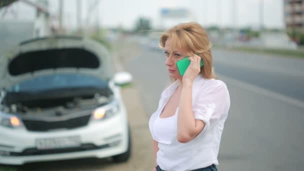 Frau und kaputtes Auto rufen per Handy um Hilfe. Kaputtes Auto auf der Straße — Stockvideo