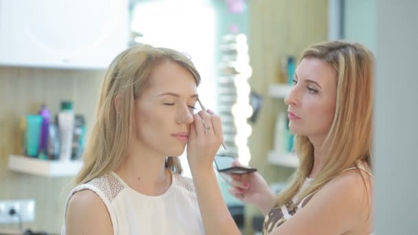 Una chica en un salón de belleza. maquilladora y peluquera trabajando en una mujer — Vídeo de stock