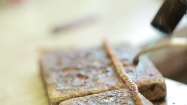 bir kuyumcu bir masanın arkasında ürün lehim. Altın zincir onarmak