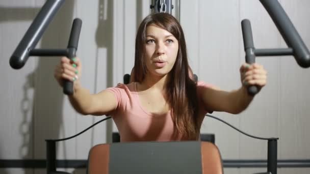 Hermosa chica entrena en el gimnasio. mujer dedicada a un simulador deportivo — Vídeos de Stock