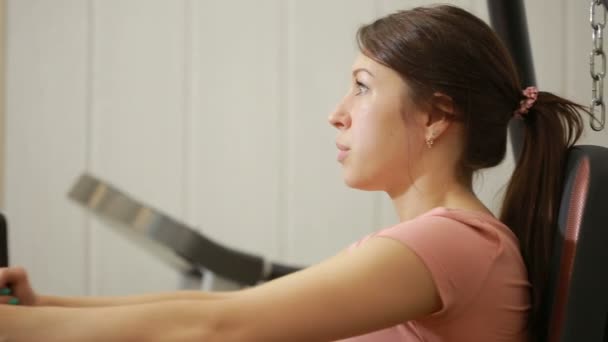 Hermosa chica entrena en el gimnasio. mujer dedicada a un simulador deportivo — Vídeo de stock