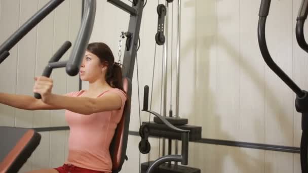 Bela menina treina no ginásio. mulher envolvida em um simulador de esportes — Vídeo de Stock