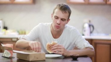 Çiğneme ve patates kızartması evde bir hamburger zevk yakışıklı adam