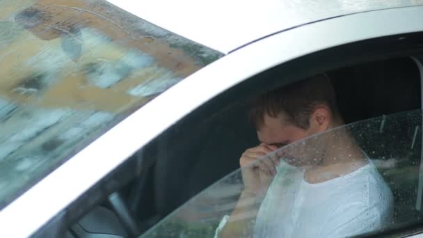 Un hombre triste llorando en el coche. lluvia en la calle. hombre histérico — Vídeos de Stock