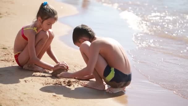 Les enfants. garçon et fille jouant avec le sable sur la plage. construire un château de sable — Video