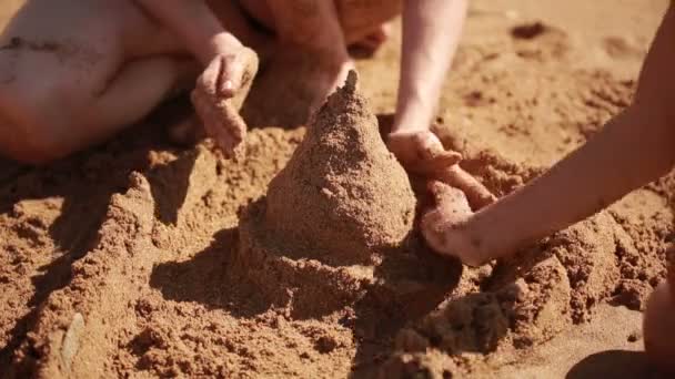 Mãe com filhos na praia. construir um castelo de areia. menino e menina — Vídeo de Stock