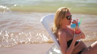 Sahilde bir kokteyl içme kadın. Deniz kenarında güneşlenirken kadın