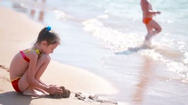 küçük kız sahilde kum ile oynuyor. Çocuk denizde. Çocuk beach
