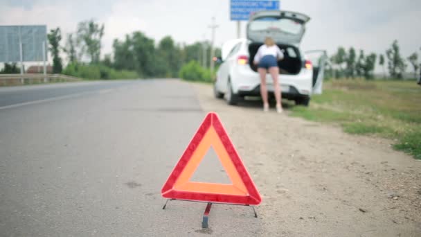 Дівчина змінює пробиту шину на машині. ремонт автомобілів на дорозі. аварія — стокове відео