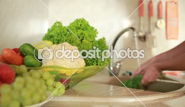 Kız üzüm yıkar. Mutfak masasındaki sebzeler. Domates ve lahana.